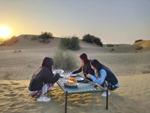 three women sitting around a table in the desert at Jaisalmer Rosu Safari in Jaisalmer