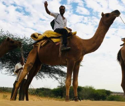 a man sitting on a camel in the desert at Jaisalmer Rosu Safari in Jaisalmer