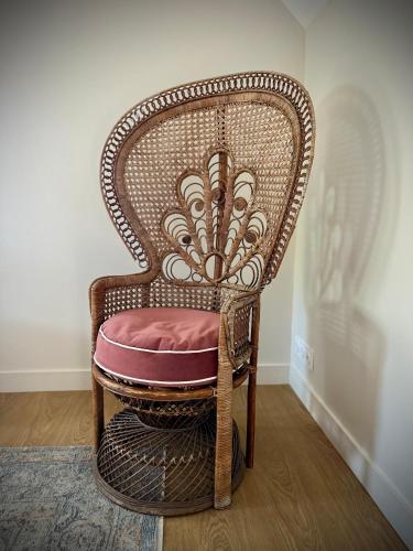 a wicker chair with a pink seat in a room at La Maison Gervaiserie & Spa in Réville