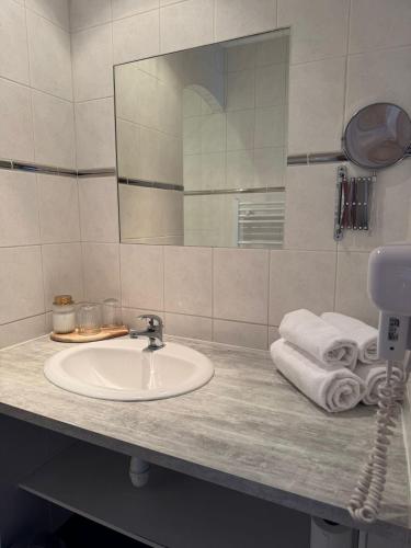 a bathroom with a sink and a mirror and towels at L'Amirauté sur Baïse in Saint-Jean-Poutge