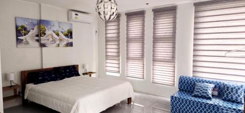 a bedroom with a bed and a chair and windows at Leribi Suites and Restaurant in Ulot