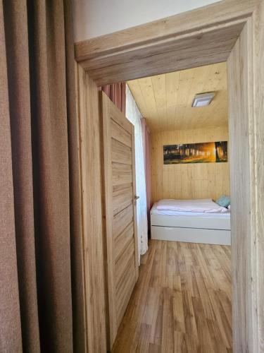 a small bedroom with a bed and a wooden door at Wellness Toliar Tatry in Stará Lesná