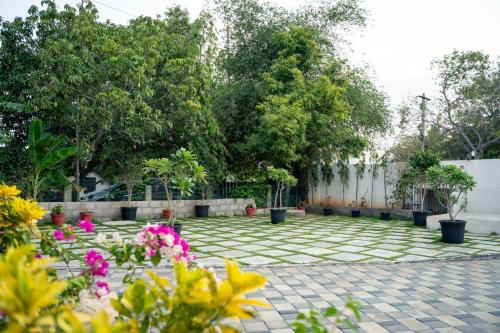 a courtyard with flowers and a fence and trees at Grandir Inn Villa in Mahabalipuram
