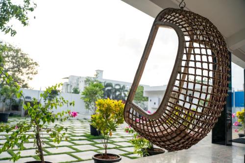 a wicker swing hanging from the ceiling of a building with plants at Grandir Inn Villa in Mahabalipuram