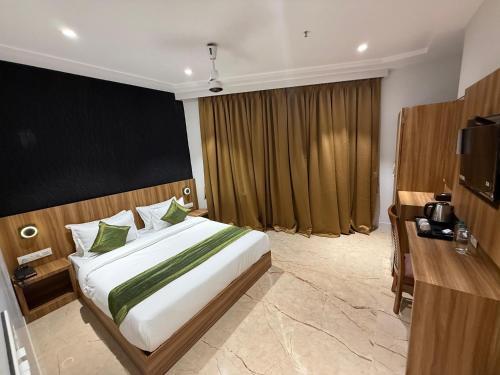 a bedroom with a large bed and a television at Hotel Alfa Suites in Mumbai