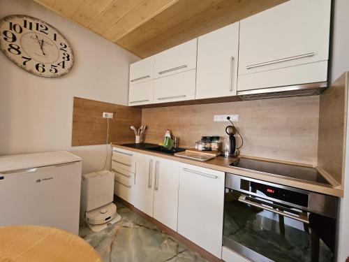 a kitchen with white cabinets and a clock on the wall at Wellness Toliar Tatry in Stará Lesná