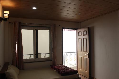 a room with a window and a door with a balcony at Nijung Homestay, Dowhill in Kurseong