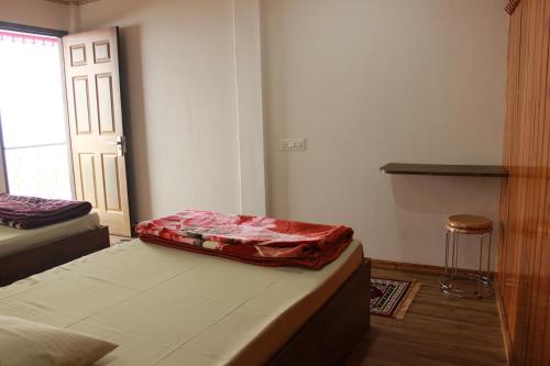 a bedroom with two beds and a door with a stool at Nijung Homestay, Dowhill in Kurseong