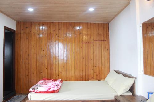 a bed in a room with a wooden wall at Nijung Homestay, Dowhill in Kurseong