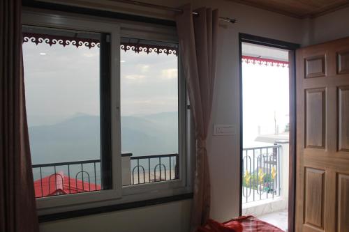 a room with a window with a view of a balcony at Nijung Homestay, Dowhill in Kurseong
