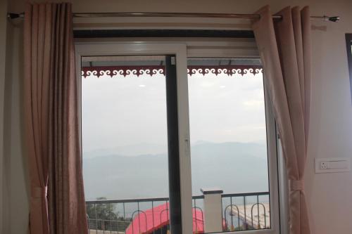 a sliding glass door with a view of a balcony at Nijung Homestay, Dowhill in Kurseong