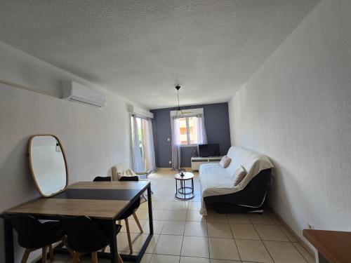 a living room with a couch and a table at Appartement dans résidence avec piscine in Agde