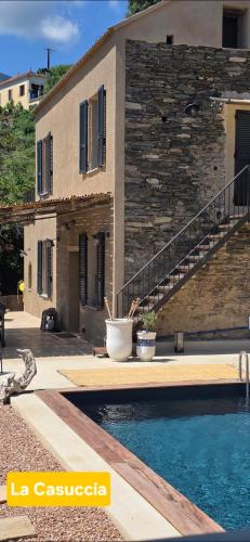 a house with a swimming pool in front of a building at A Pasturella, Jacuzzi Spa in Venzolasca