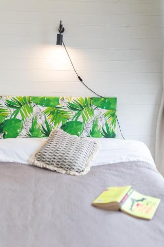 a bed with a green pillow and a book on it at Domki Acapulco nad morzem Rewal in Rewal