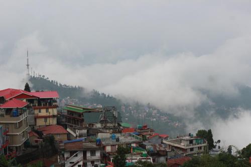 a group of buildings on a hill in the fog at Nijung Homestay, Dowhill in Kurseong