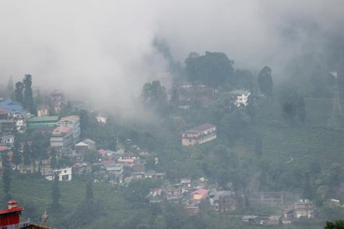 a town on a hill in the fog with houses at Nijung Homestay, Dowhill in Kurseong