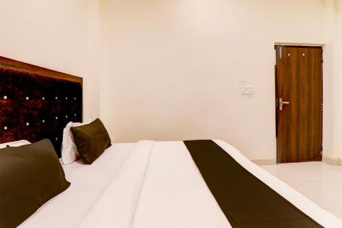 a bedroom with a white bed with a wooden door at Hotel O KAILASHA INN in Hasanganj
