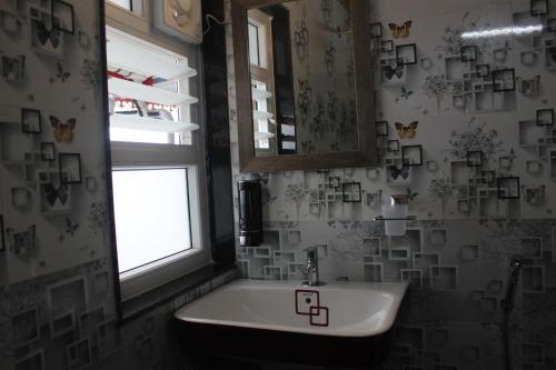 a bathroom with a sink and a mirror and a window at Nijung Homestay, Dowhill in Kurseong