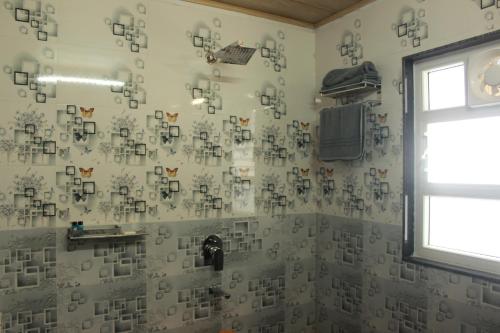 a bathroom with a shower with white tiles on the wall at Nijung Homestay, Dowhill in Kurseong