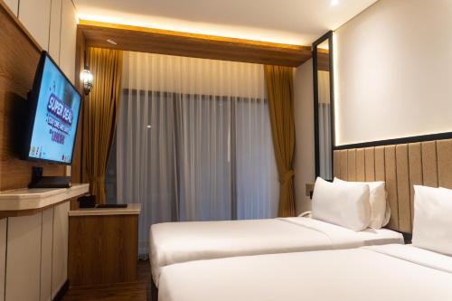 a hotel room with two beds and a flat screen tv at Grand Sunshine Resort & Convention in Bandung