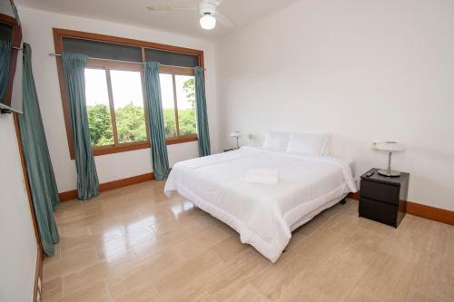 a bedroom with a white bed and a large window at Espectacular Apto en Casa de Campo Los Altos 3 in La Romana
