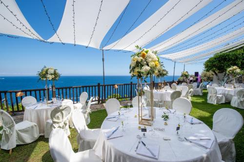 a wedding reception with white tables and chairs and the ocean at Hotel Costa Diva in Praiano