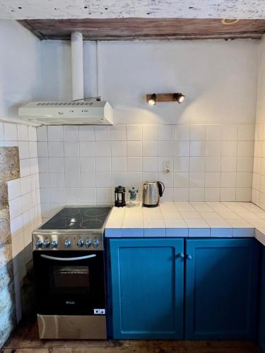 a kitchen with blue cabinets and a stove at Gîte La Vésarnie in Montaigu-de-Quercy