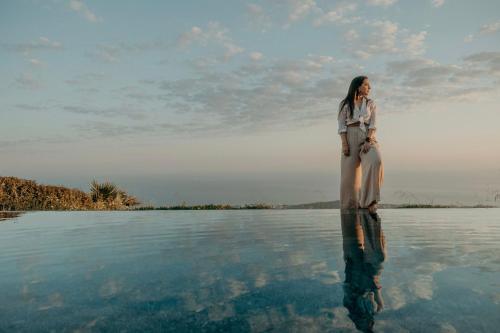 a woman is standing in the water at Santorini Sky, Luxury Resort in Pirgos