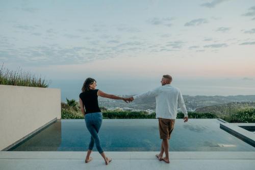 a man and woman holding hands while standing on top of a house at Santorini Sky, Luxury Resort in Pirgos
