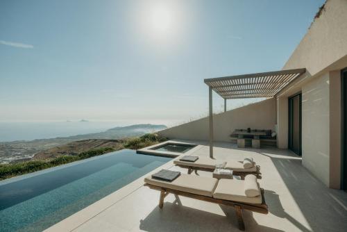 a villa with a swimming pool and a patio with a bed at Santorini Sky, Luxury Resort in Pirgos