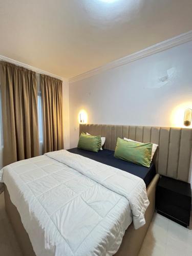 a bedroom with a large bed with two green pillows at 3 Bedroom Apartment in Lakowe Lakes and Golf course in Ajibade