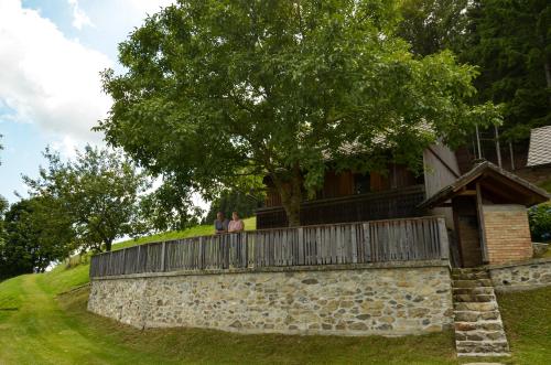 two people standing on a stone wall in front of a house at Koča v Lozah in Gornji Grad