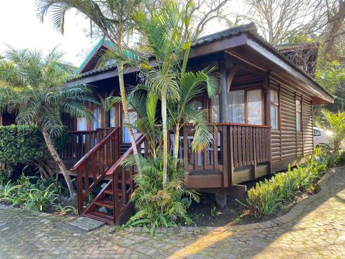 a small wooden house with palm trees in front of it at Knysna Retreat - Knysna River Club in Knysna