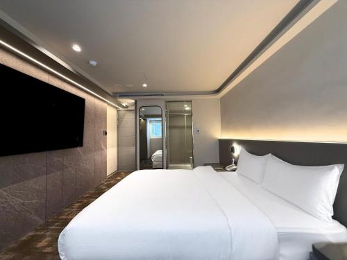 a bedroom with a large white bed and a flat screen tv at Hub Hotel Ximen-inn Kunming in Taipei