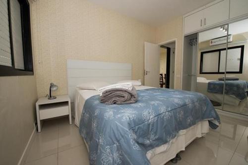 a bedroom with a bed with a blue blanket on it at Apart Hotel Barra Bela Barra da Tijuca in Rio de Janeiro