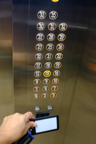 a person holding a cell phone in front of an elevator with a row of numbers at Z Loft Skyhouse BSD in Samporo
