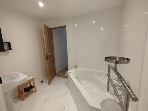 a white bathroom with a tub and a sink at Les Communs de Chiffrevast in Tamerville