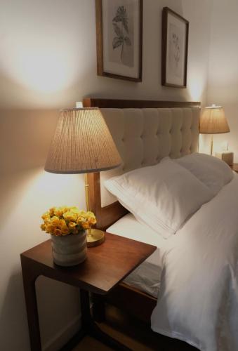ein Bett mit einem Tisch, auf dem eine Lampe und Blumen stehen in der Unterkunft Brooklyn Hideaway in Brooklyn