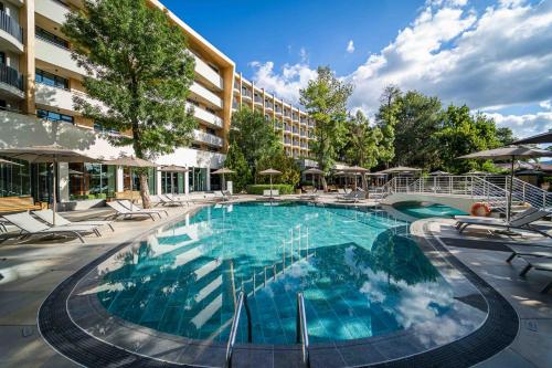 a large swimming pool with chairs and a building at HVD Club Bor Ultra All Inclusive - Private Beach & Free parking in Sunny Beach