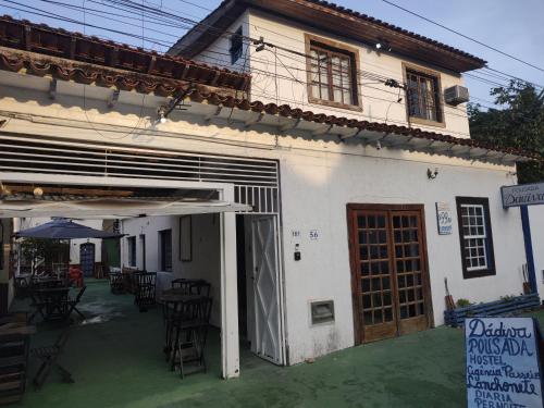 a white house with an open door and a patio at Pousada Dádiva Retiro Beira Mar Rosas Paraty Centro in Paraty