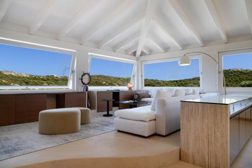 a living room with white furniture and large windows at Villa Elicriso in Olbia