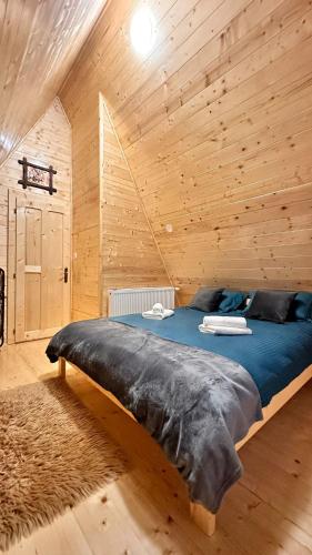 a large bed in a room with a wooden wall at A Frame Panoramic Dundy in Dealu Muntelui