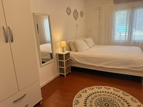 a small bedroom with a bed and a mirror at סתלבט בקיבוץ in Hagoshrim