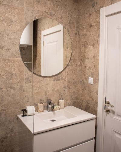 a bathroom with a white sink and a mirror at Ohanas Apartment in Prishtinë