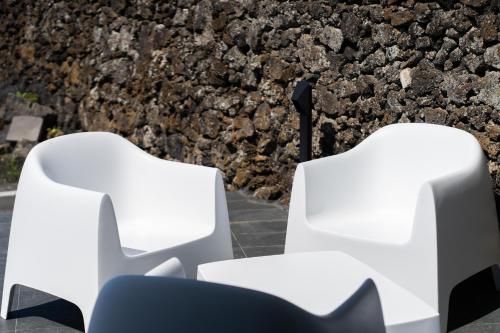 two white chairs in front of a stone wall at Oceanside Village 1 in Lagoa