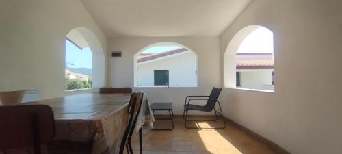 a dining room with two windows and a table and chairs at Sole e Luna in San Vito
