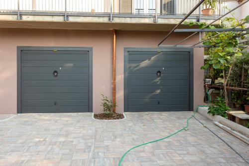 two garage doors on a building with a green hose at Residence Risorgimento in Novara