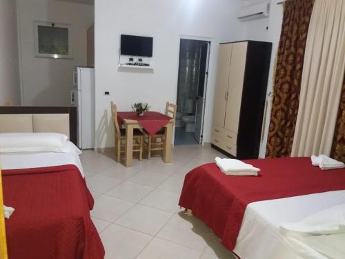 a hotel room with two beds and a table and a kitchen at Hotel Gezimi in Margjonaj