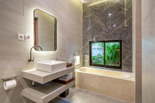 a bathroom with a sink and a tub and a mirror at Bramasta Villa in Ubud