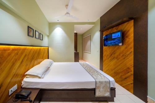 a bedroom with a bed with a tv on the wall at Hotel Dolphin Puri in Puri
